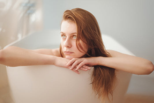 A woman sitting in a bathtub with her arms on the edge of the tub