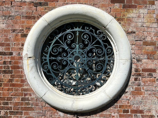 A round window with decorative metal grille.