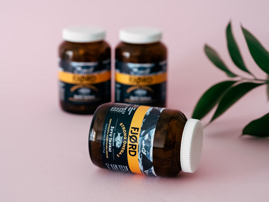 three bottles of fish oil sitting next to a plant