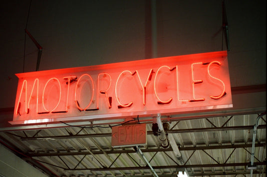 a neon sign that reads motorcycles hanging from a ceiling