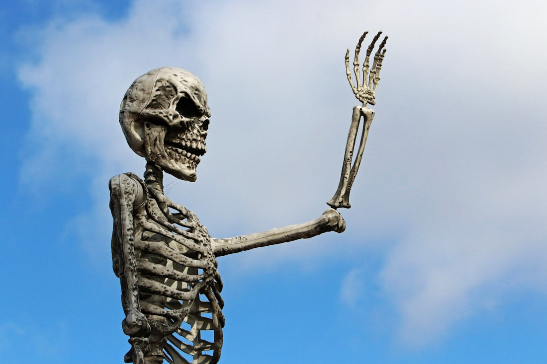 A skeleton with raised hand against blue sky