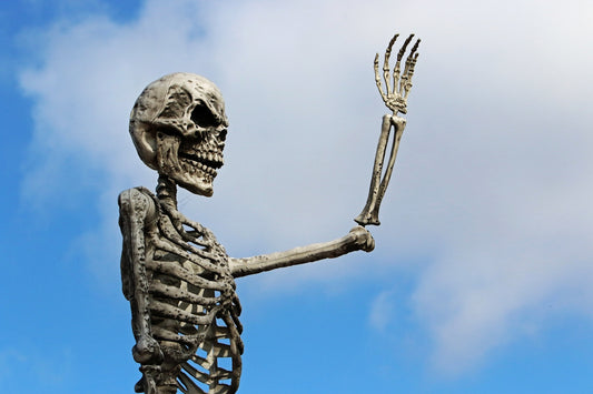 A skeleton with raised hand against blue sky